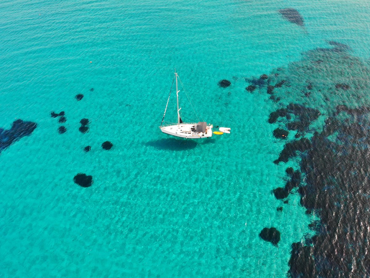 Aerial view of a sailboat in turquoise Sardinian waters