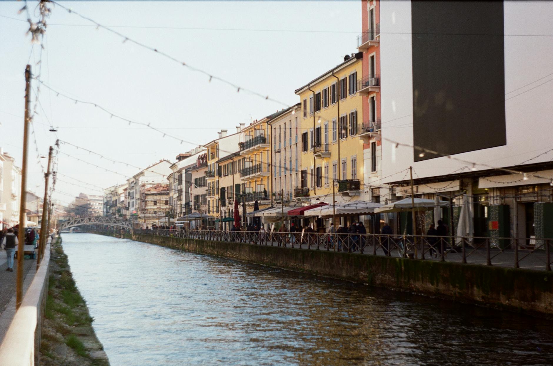 Navigli canal street with shops and string lights at dusk in Milan