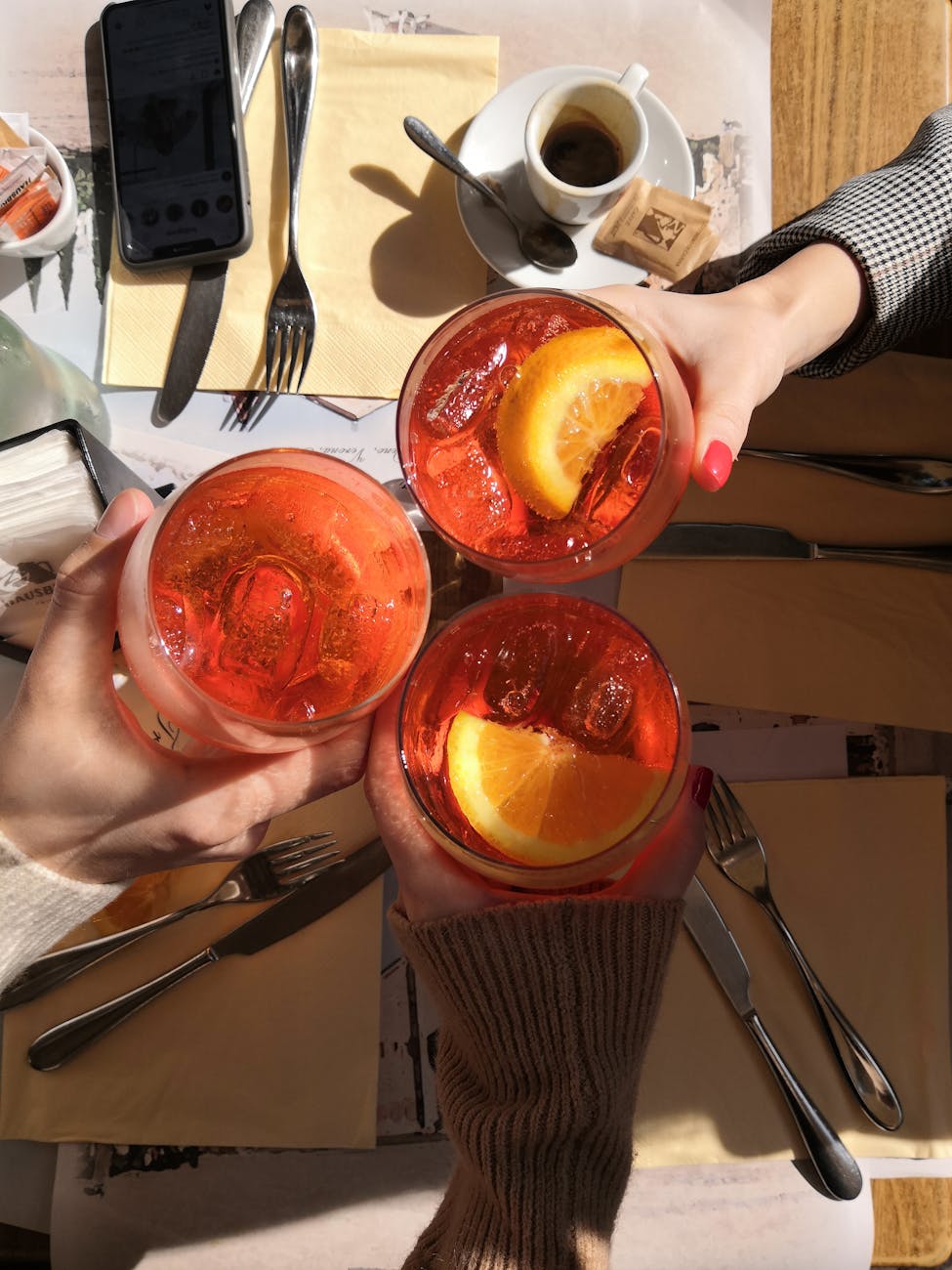 Friends toasting with Aperol Spritz drinks at an outdoor Italian cafe
