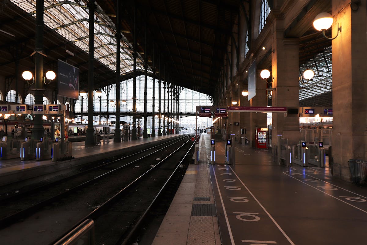The grand glass and iron interior of a Paris train station with travellers on the platform