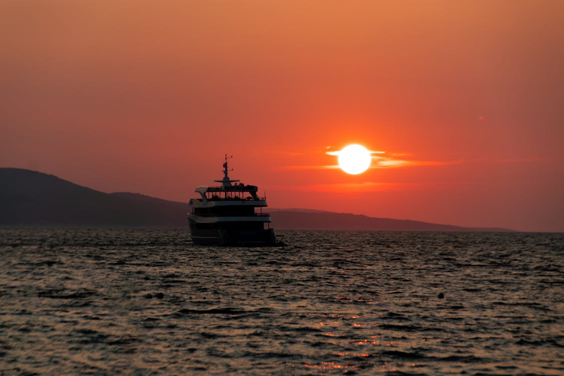Boat silhouetted against Mediterranean sunset with orange sky