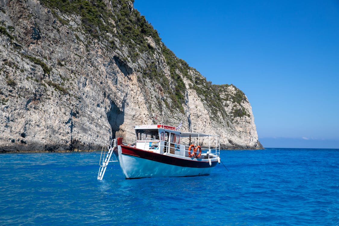 Tour boat cruising along the dramatic white cliffs of Zakynthos island coast