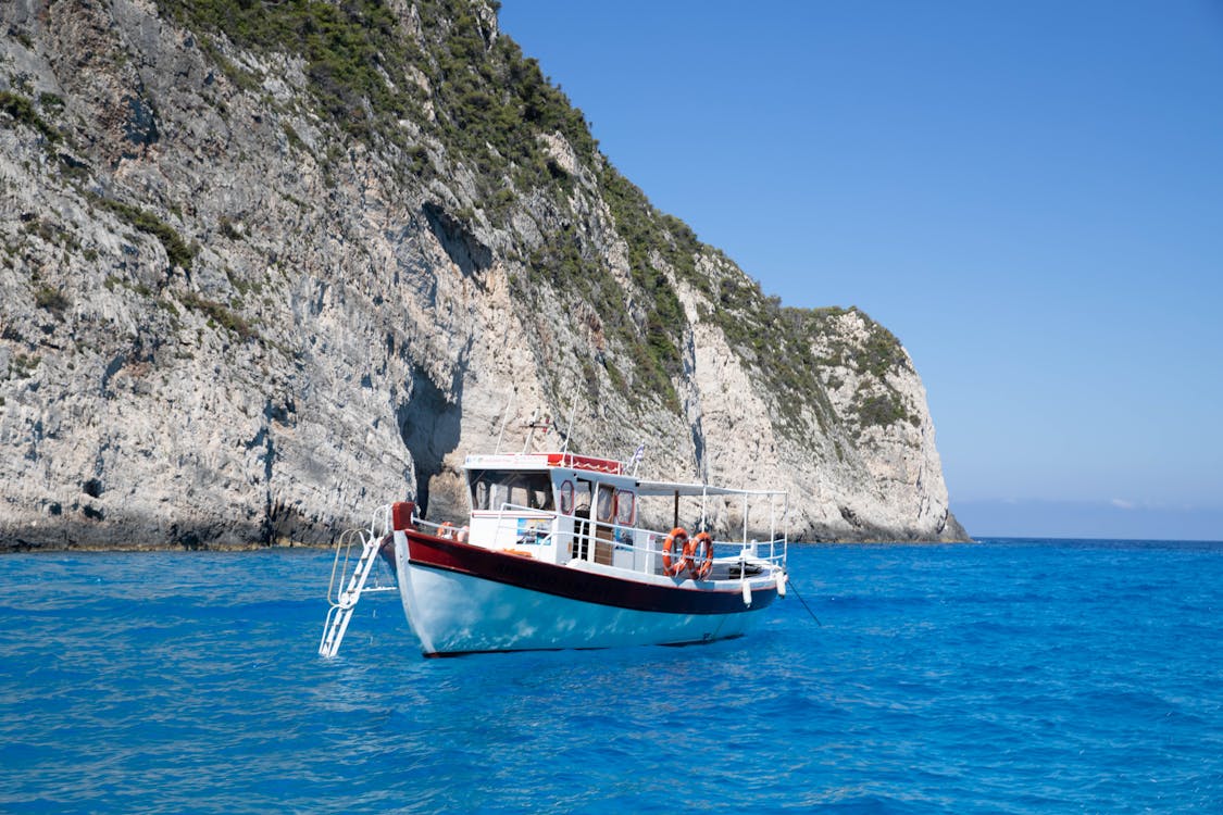 A boat sailing near towering white cliffs along the Zakynthos coastline