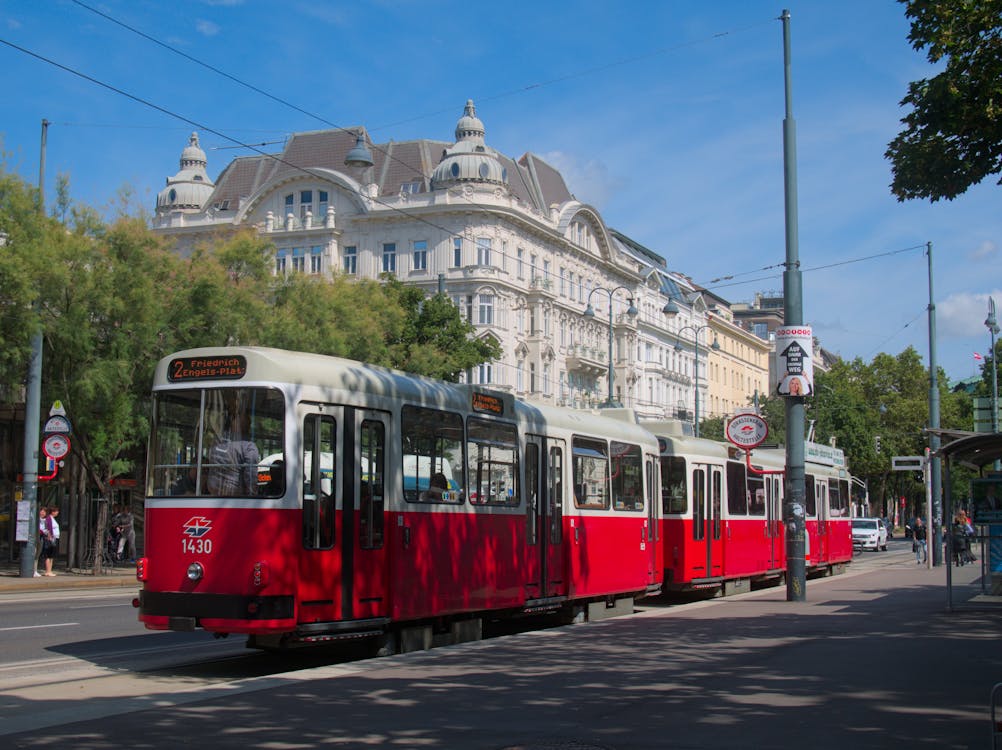 Red tram on a Vienna street with buildings and blue sky