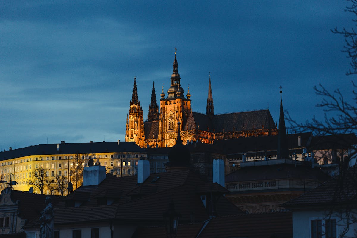 Prague Castle illuminated against the evening sky from across the Vltava River