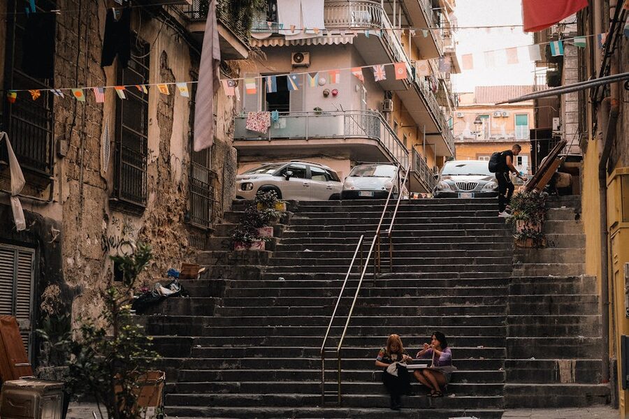 Pedestrians walking on outdoor stone stairs in a Naples neighbourhood