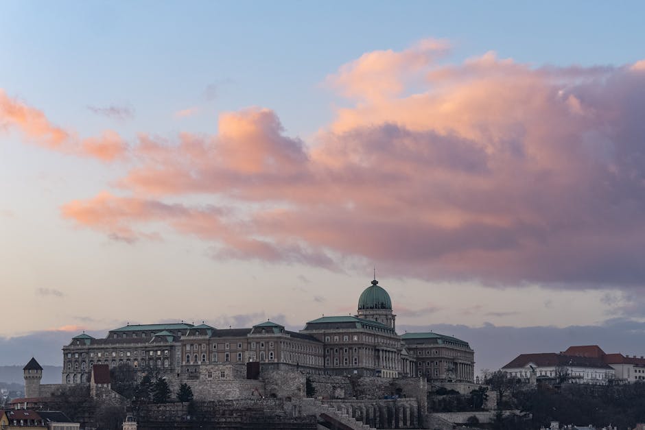 Buda Castle silhouetted against a dramatic sunset sky over Budapest