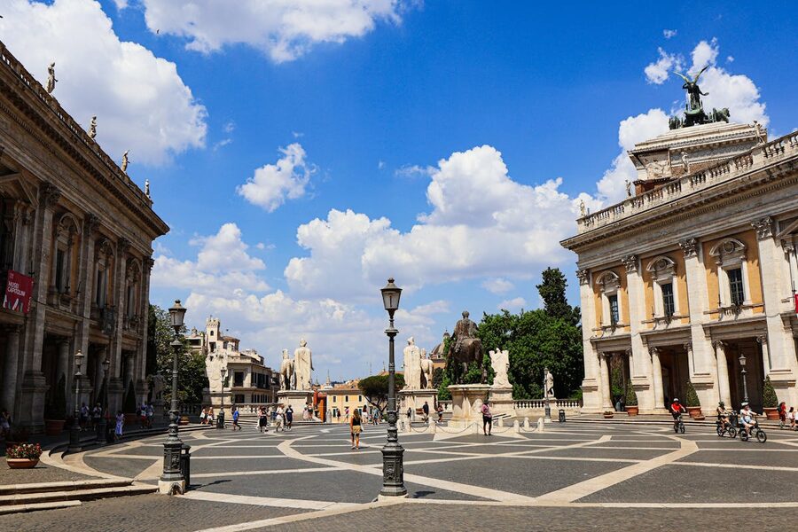 Tourists exploring Piazza del Campidoglio on Capitoline Hill in Rome under a bright sky