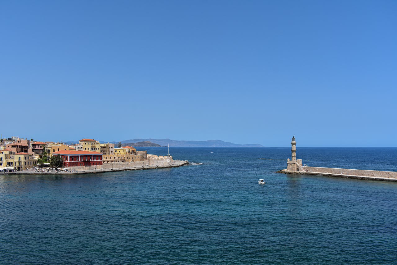 Scenic view of Chania harbor with the historic lighthouse under clear blue skies