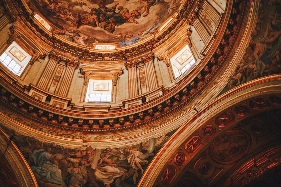 Ornate Baroque dome interior with detailed religious frescoes and gold architectural elements in Naples
