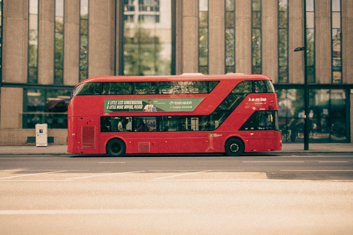 A red double-decker bus driving through central London streets