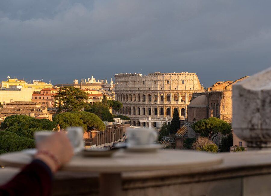View of the Colosseum at sunset from a cafe table with coffee cups in the foreground