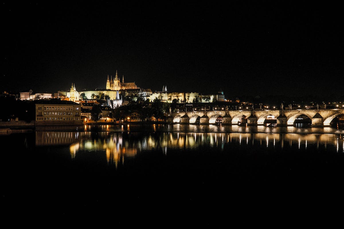 Night view of Prague Castle and Charles Bridge reflecting on the Vltava River