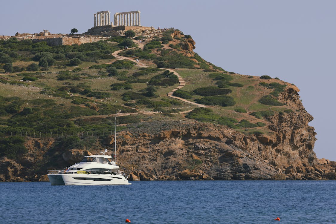 Scenic view of Temple of Poseidon with a yacht sailing below at Cape Sounion