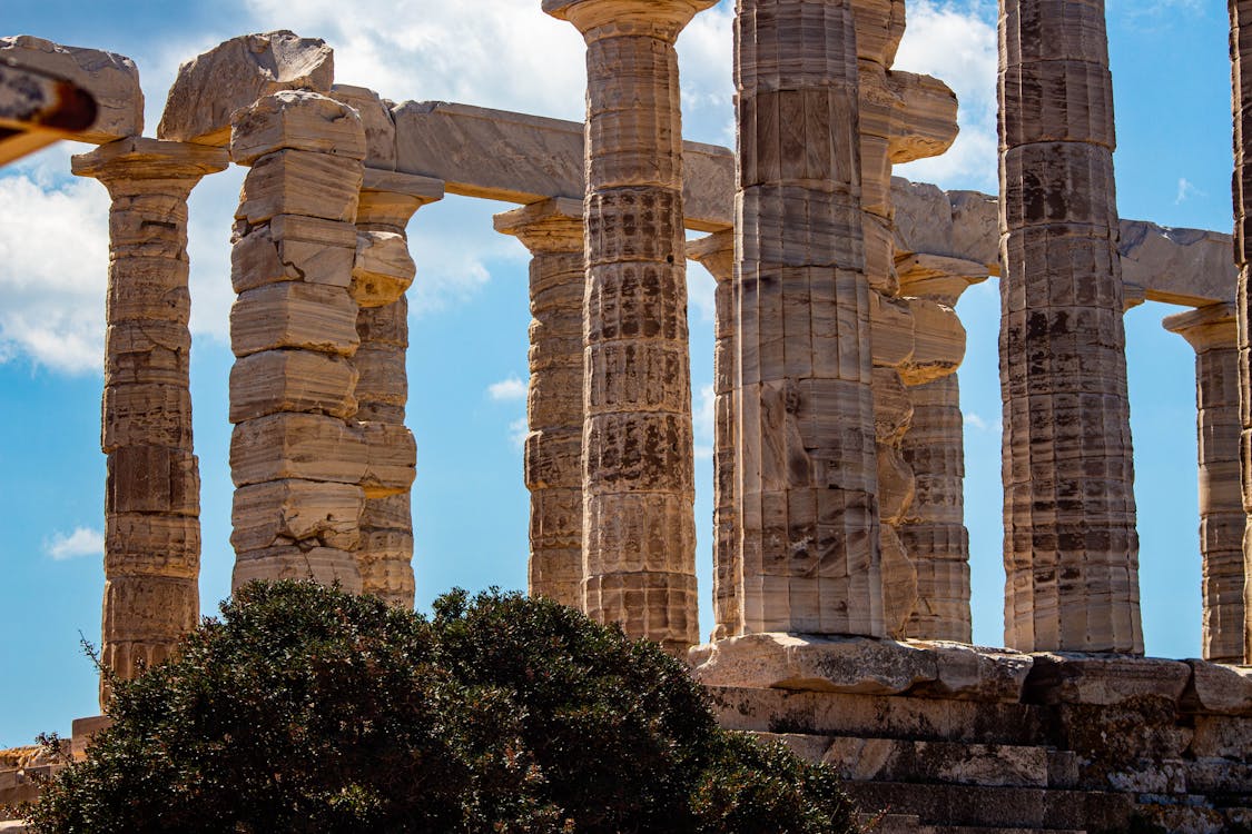 Ancient Greek temple columns under a bright blue sky at Sounion