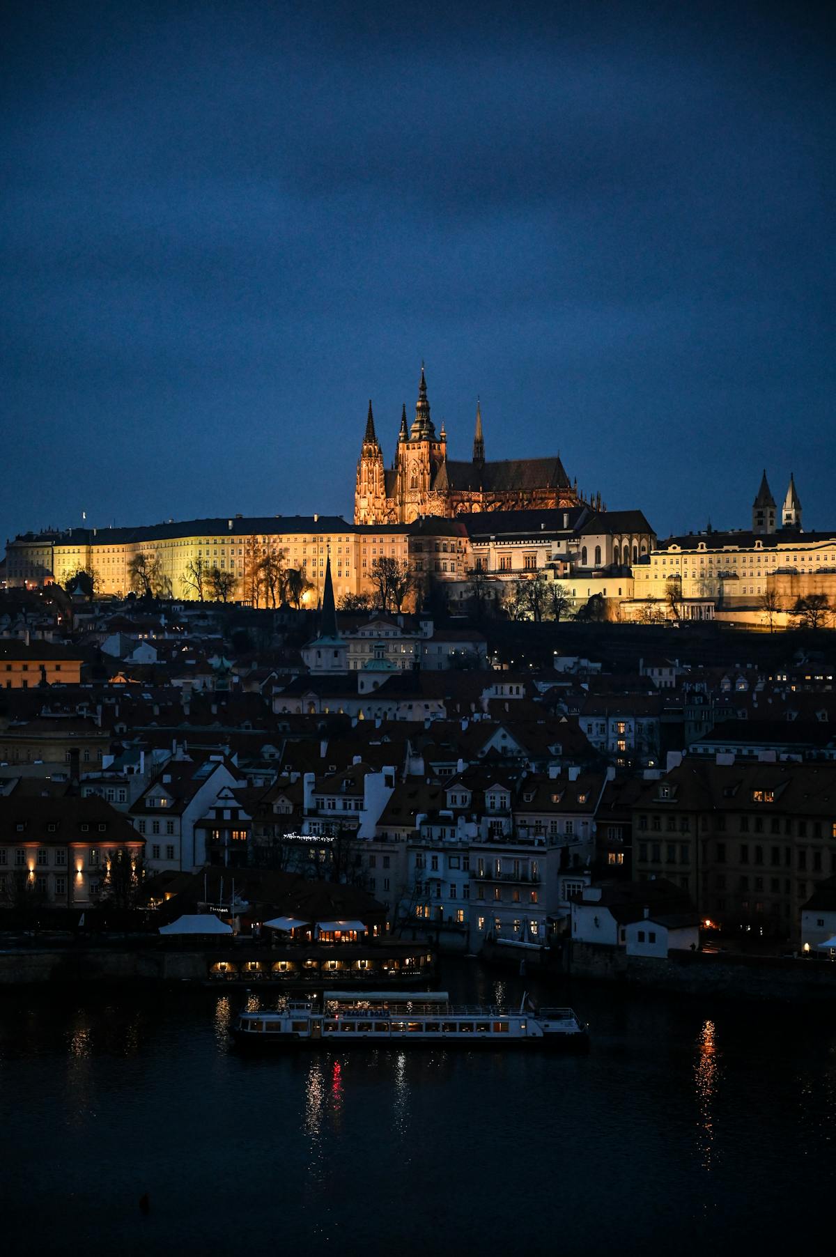 Twilight view of Prague Castle illuminated at dusk overlooking the Vltava River