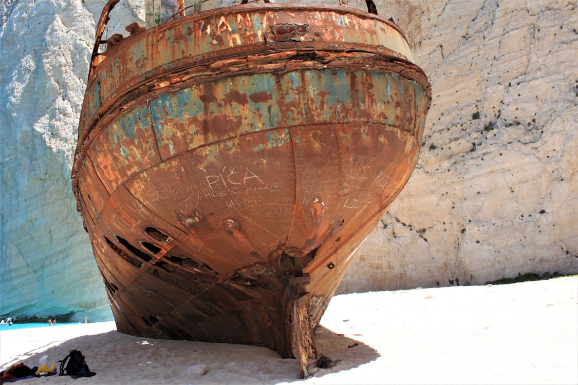 The rusting MV Panagiotis shipwreck on white sand at Navagio Beach with towering cliffs behind