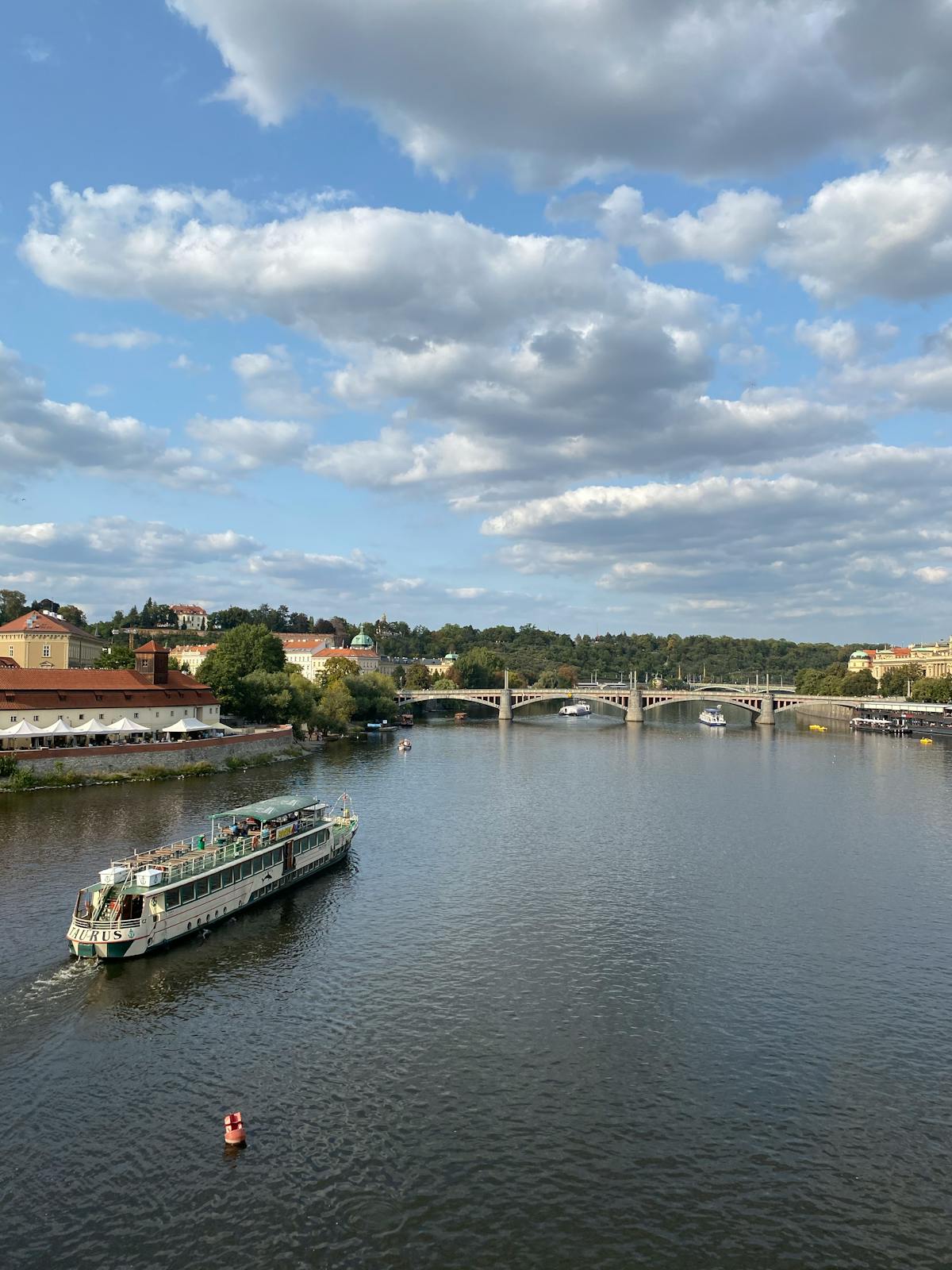 Aerial view of a boat cruising on the Vltava River with bridges and Prague cityscape