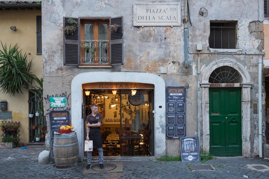 Rustic restaurant entrance in the Trastevere neighborhood of Rome with traditional Italian street scene