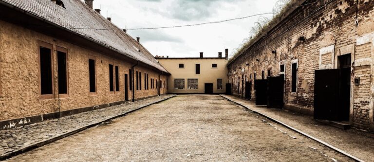 An abandoned courtyard within the Terezin fortress showing weathered stone walls and cobblestones