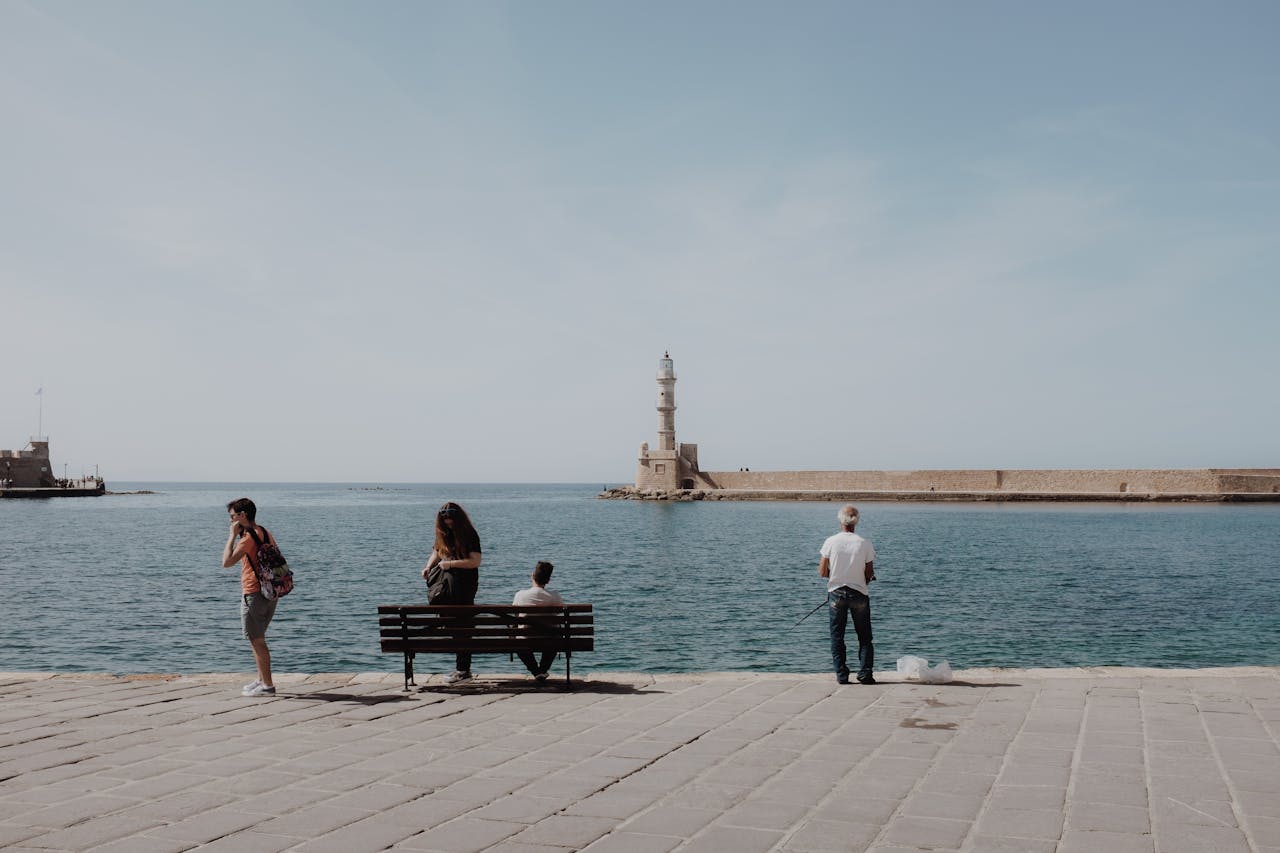 The historic Chania lighthouse with people enjoying the seaside on a sunny day in Crete