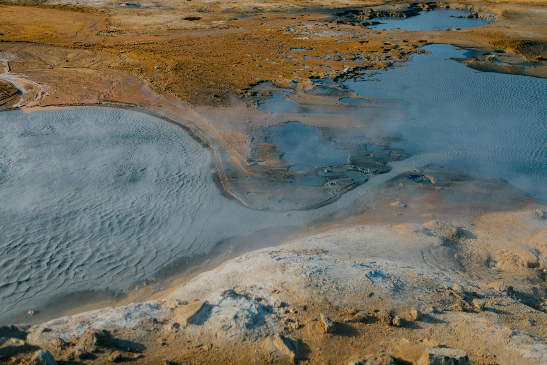 Aerial view of Icelandic geothermal landscape with barren terrain and steaming hot springs