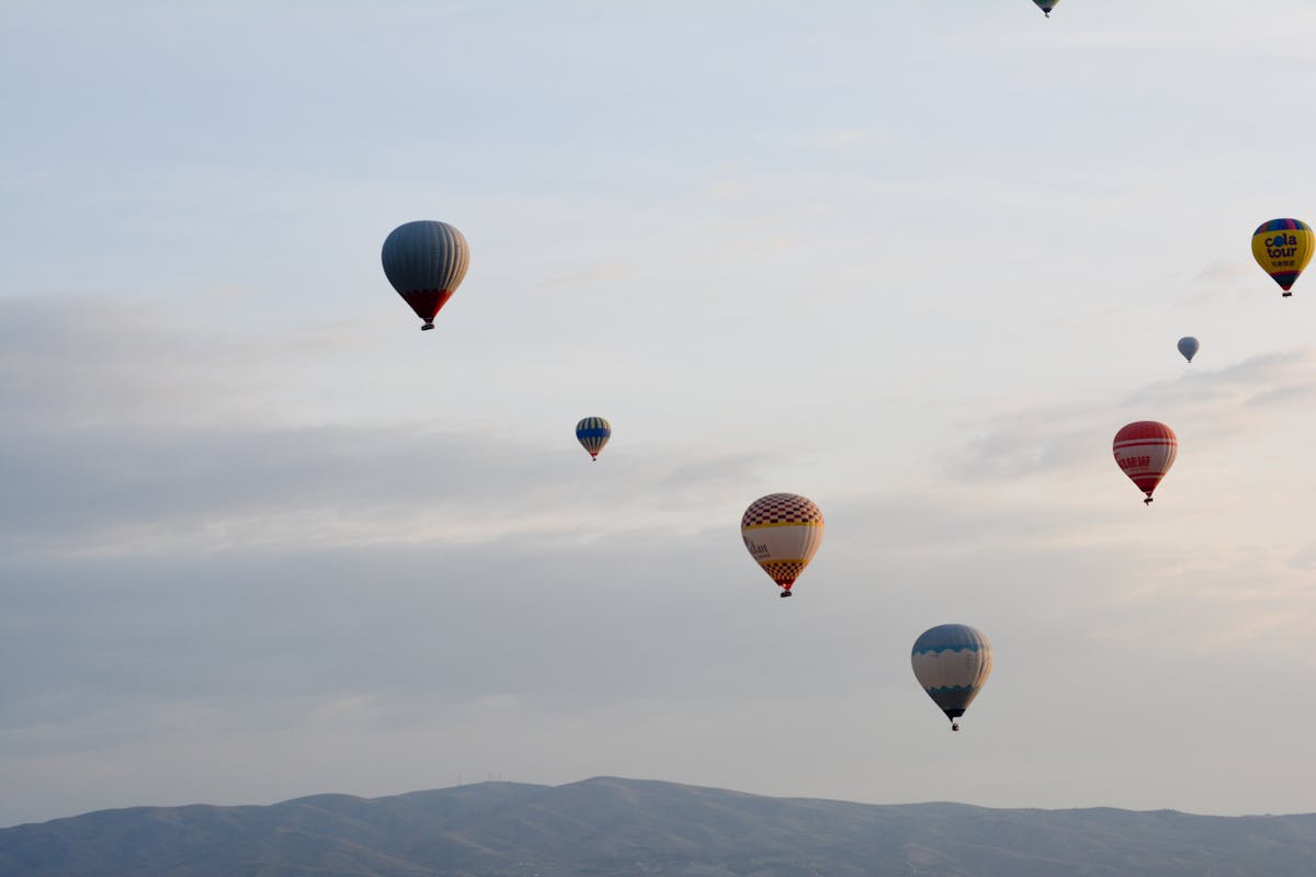 Colorful hot air balloons drifting above Cappadocia landscape at sunrise in Turkey