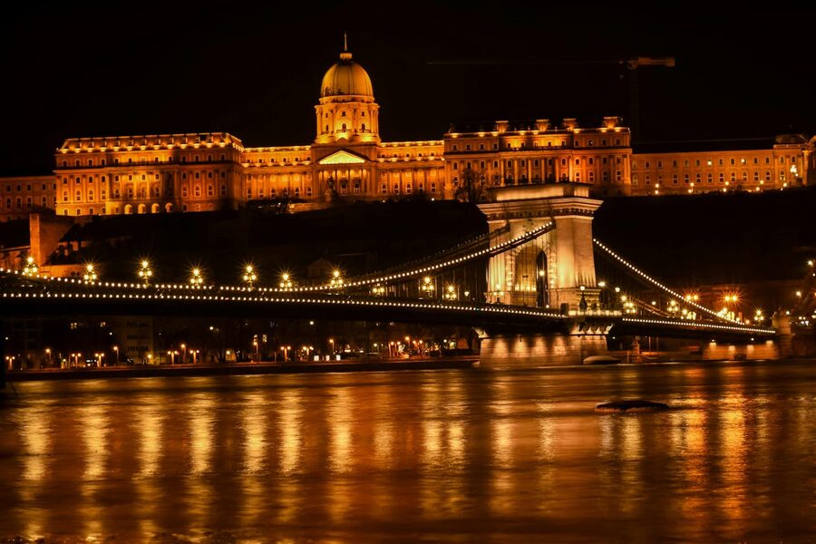 Buda Castle and Chain Bridge illuminated at night reflecting in the Danube River Budapest