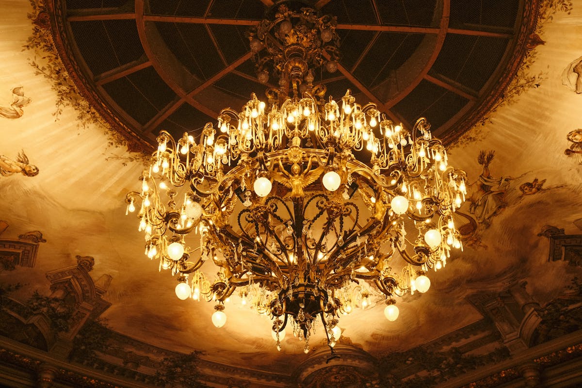 Opulent chandelier in grand ballroom with baroque architecture and decorative ceiling