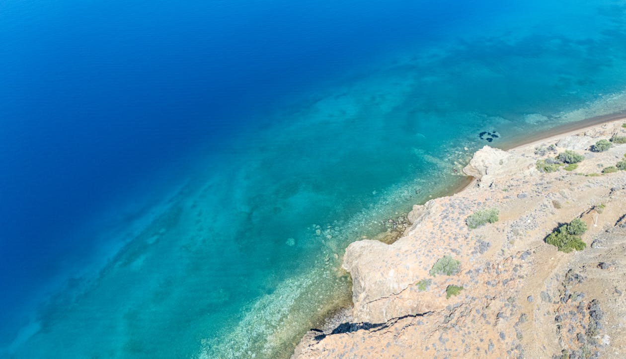 Stunning aerial shot of a rocky shoreline meeting clear turquoise waters in Greece