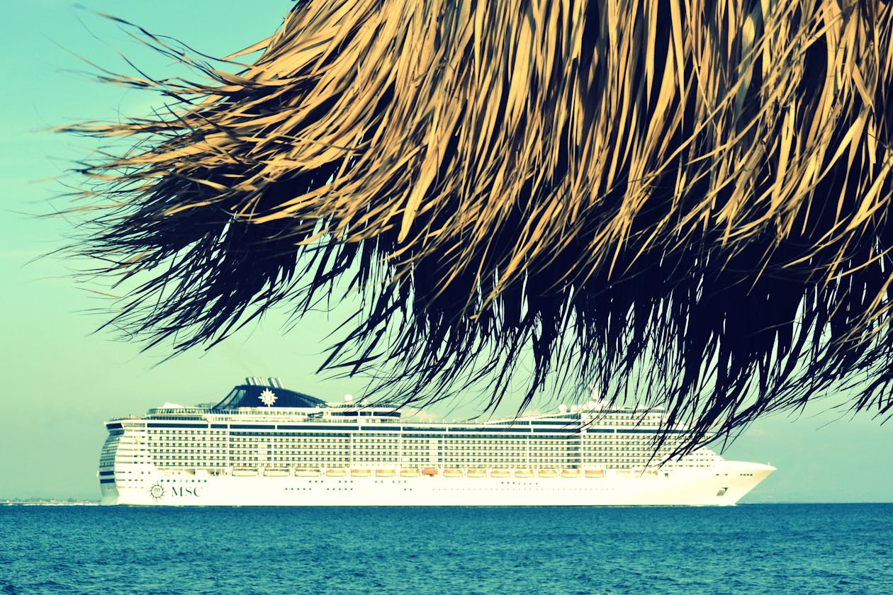 A cruise ship anchored near a tropical Greek beach under clear skies