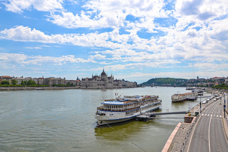 Panoramic view of cruise ships docked on the Danube River with Hungarian Parliament Building in Budapest