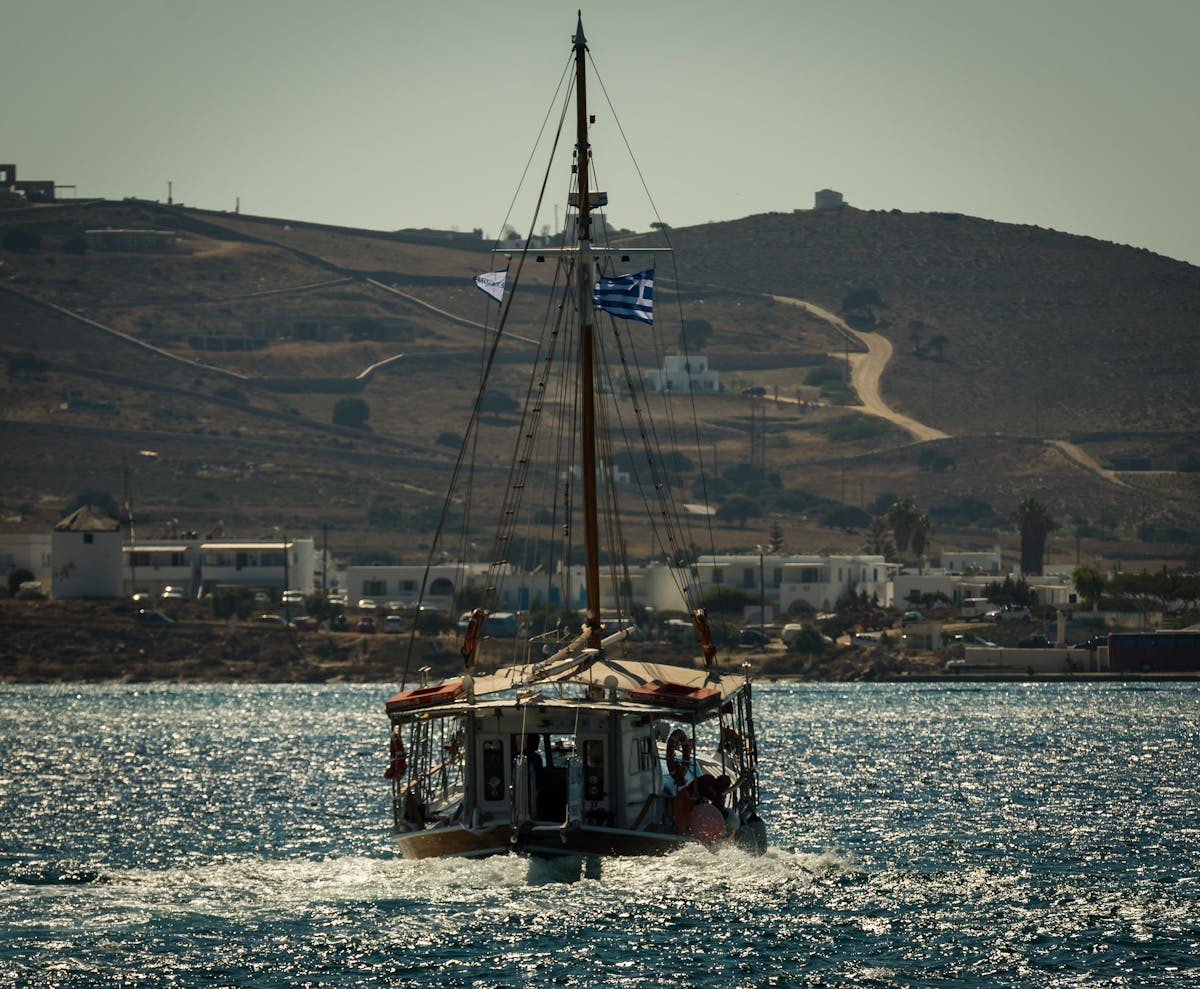 A traditional Greek sailing boat with a flag cruising on the Aegean Sea