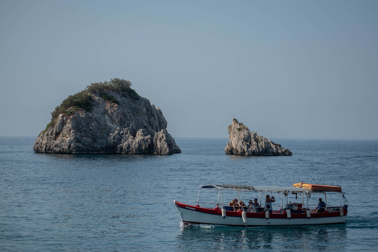 Small boat carrying passengers past rocky Greek islands on a sunny day