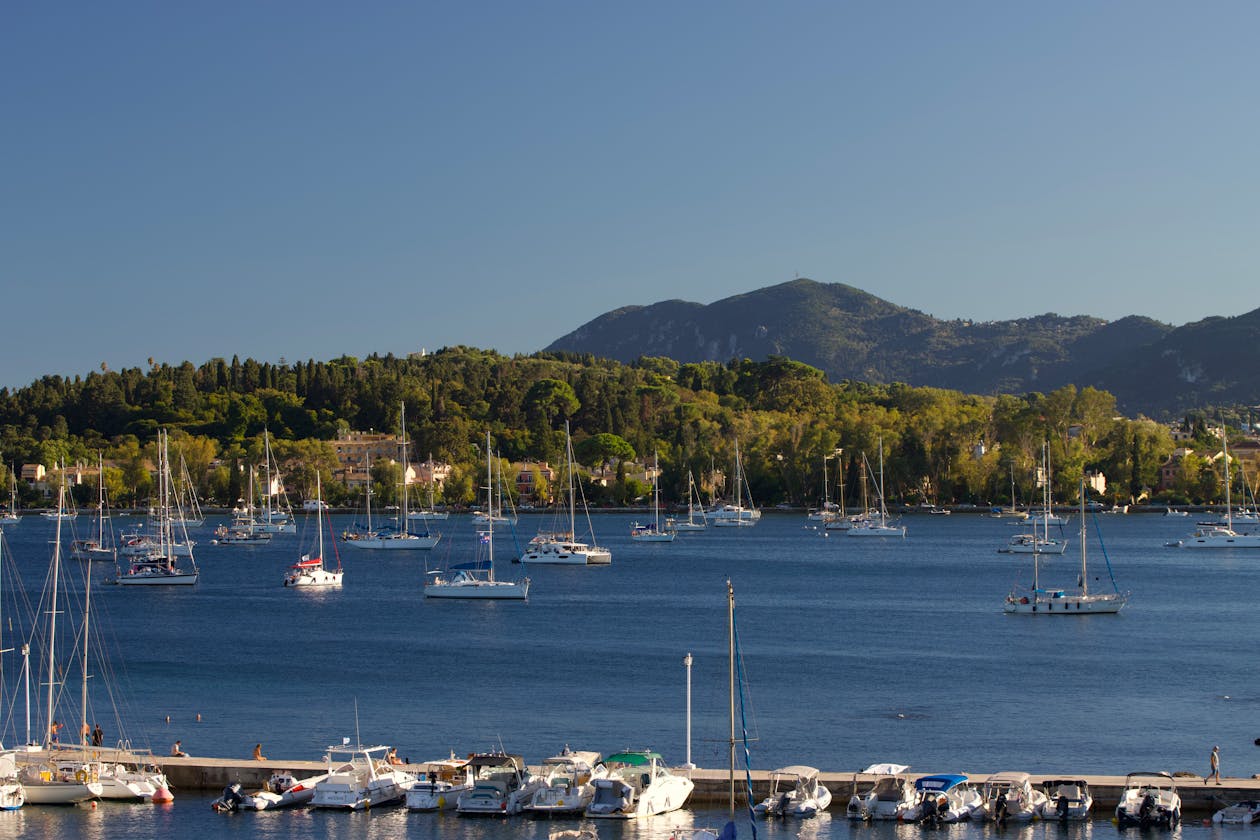 Boats anchored in a Greek harbor with green hills in the background