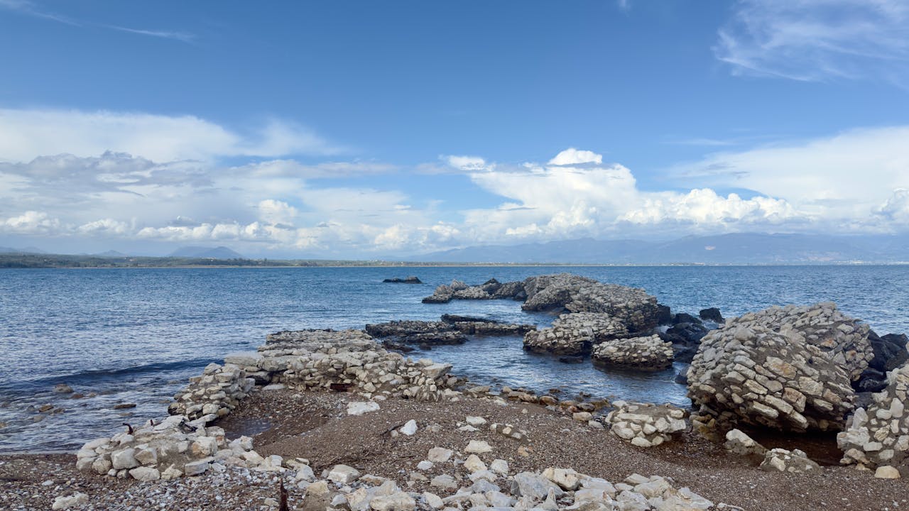 Ancient stone ruins on the Greek coast overlooking a calm blue sea