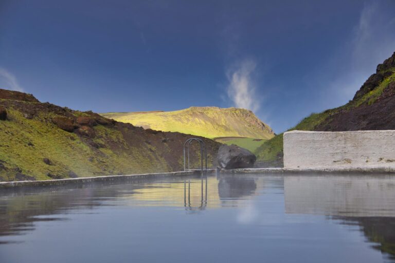 Relaxing hot spring pool in scenic Icelandic mountains with clear blue sky