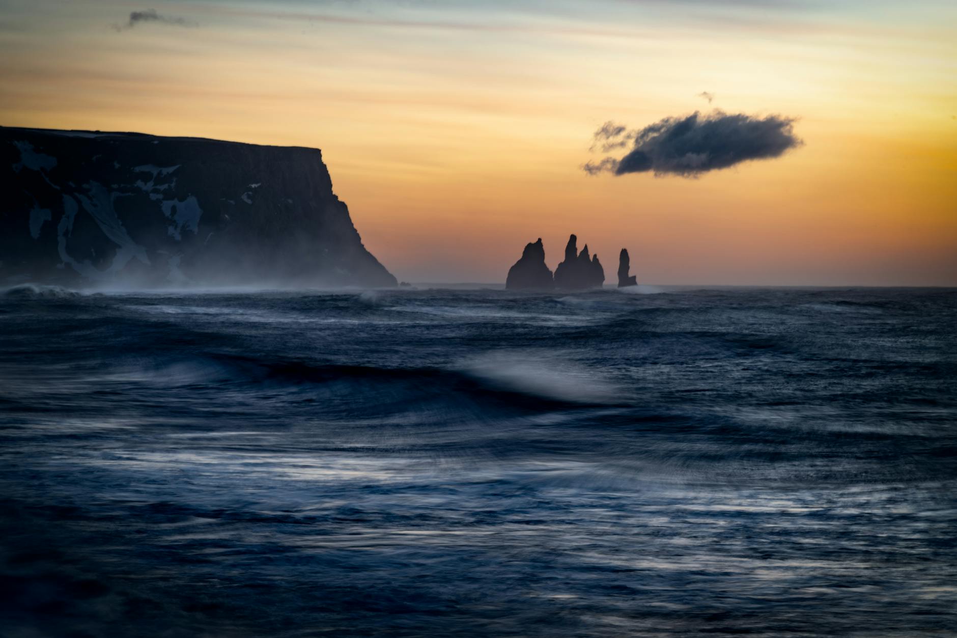Stunning sunset at Iceland coastline with rock formations and ocean waves