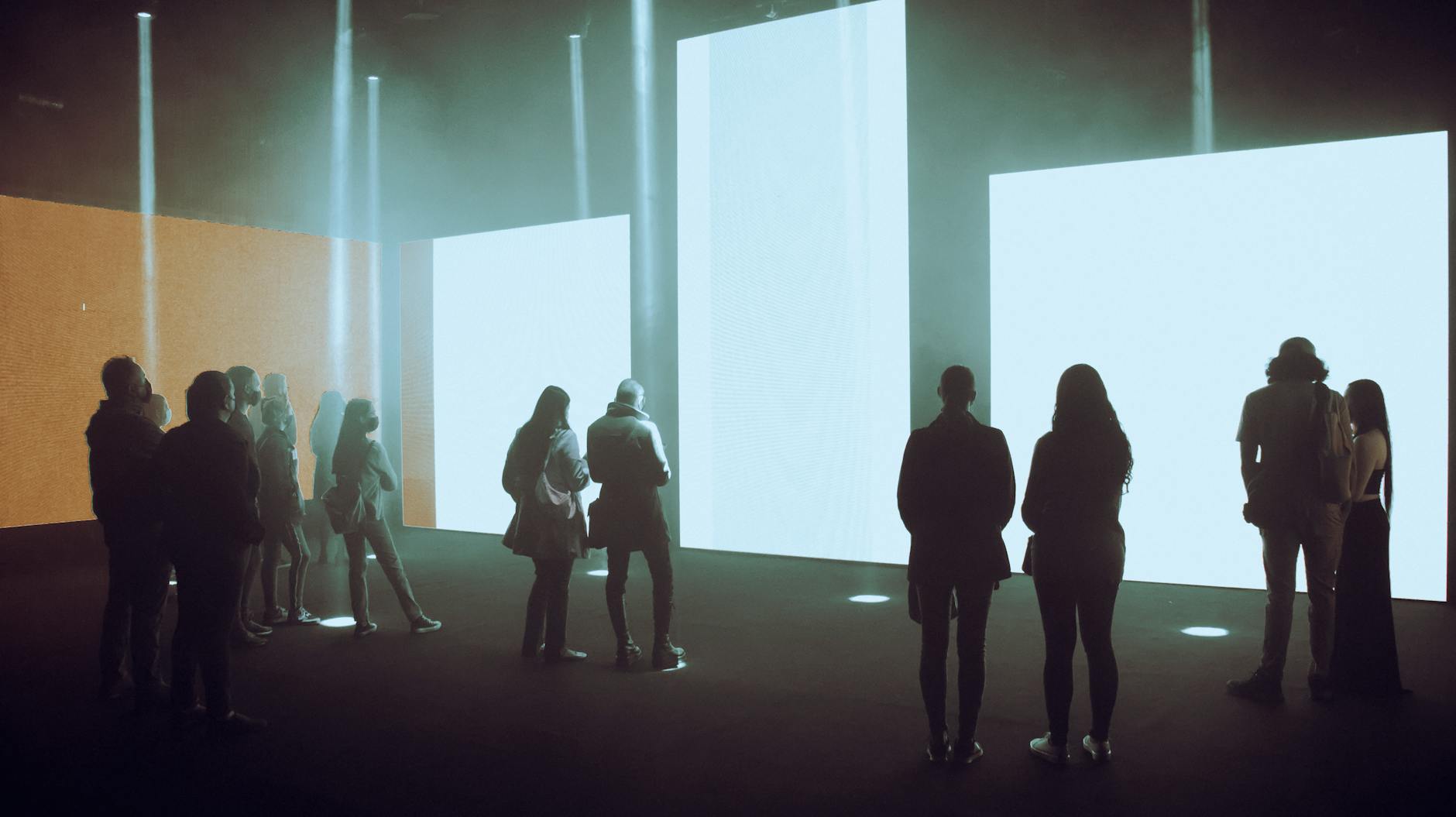 People walking through an immersive digital art exhibition with projected artwork on walls