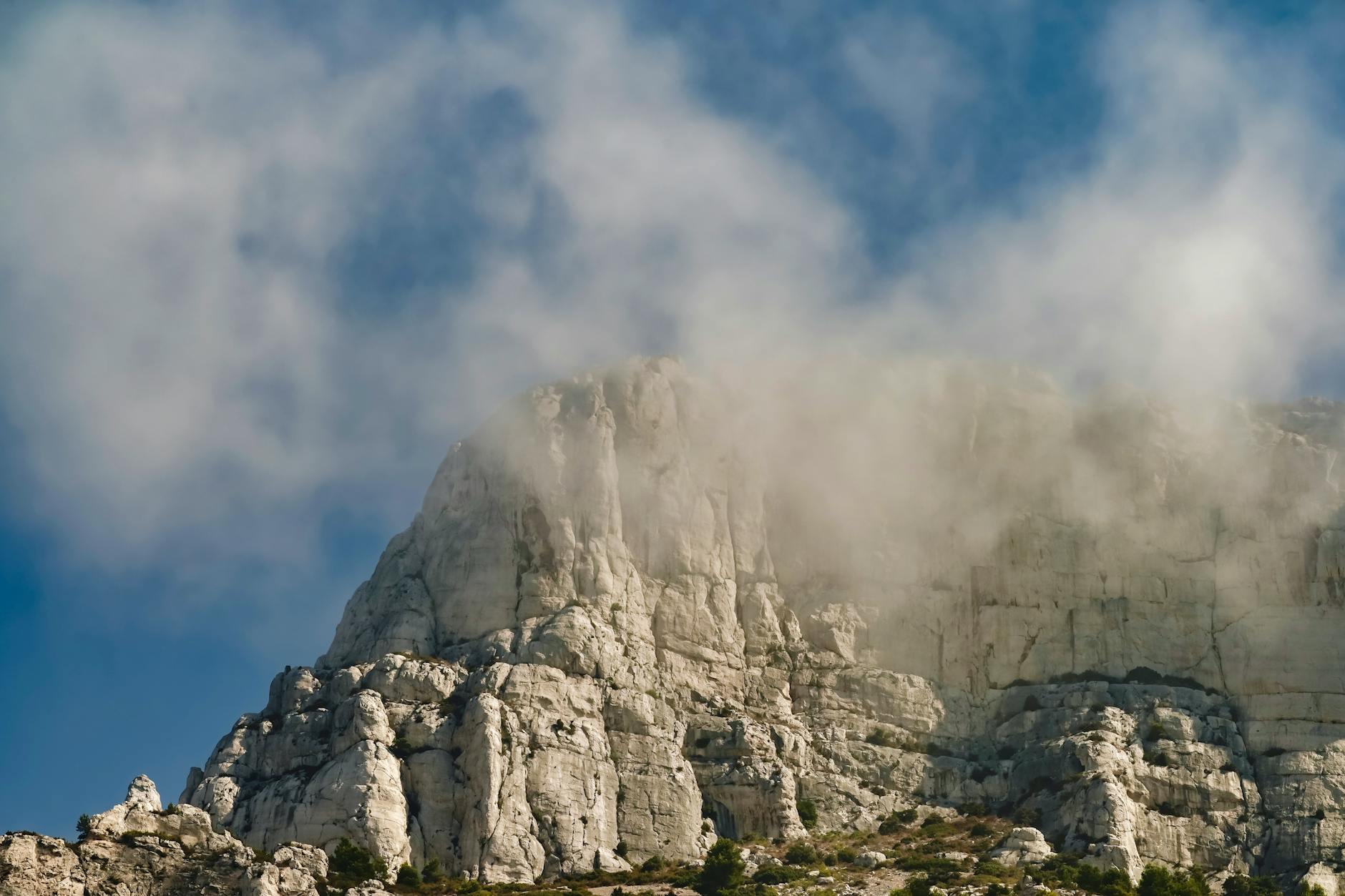 Tall limestone cliff faces in Provence partially covered by mist and clouds