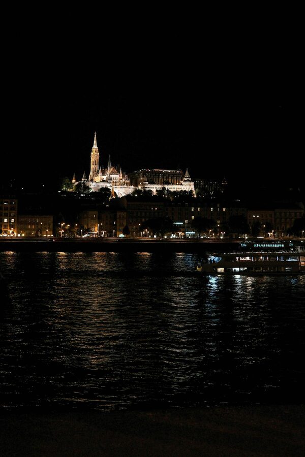 Matthias Church and Buda Castle illuminated at night across the Danube in Budapest