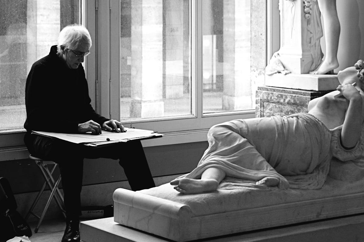 Visitor sketching a classical statue inside a Paris museum