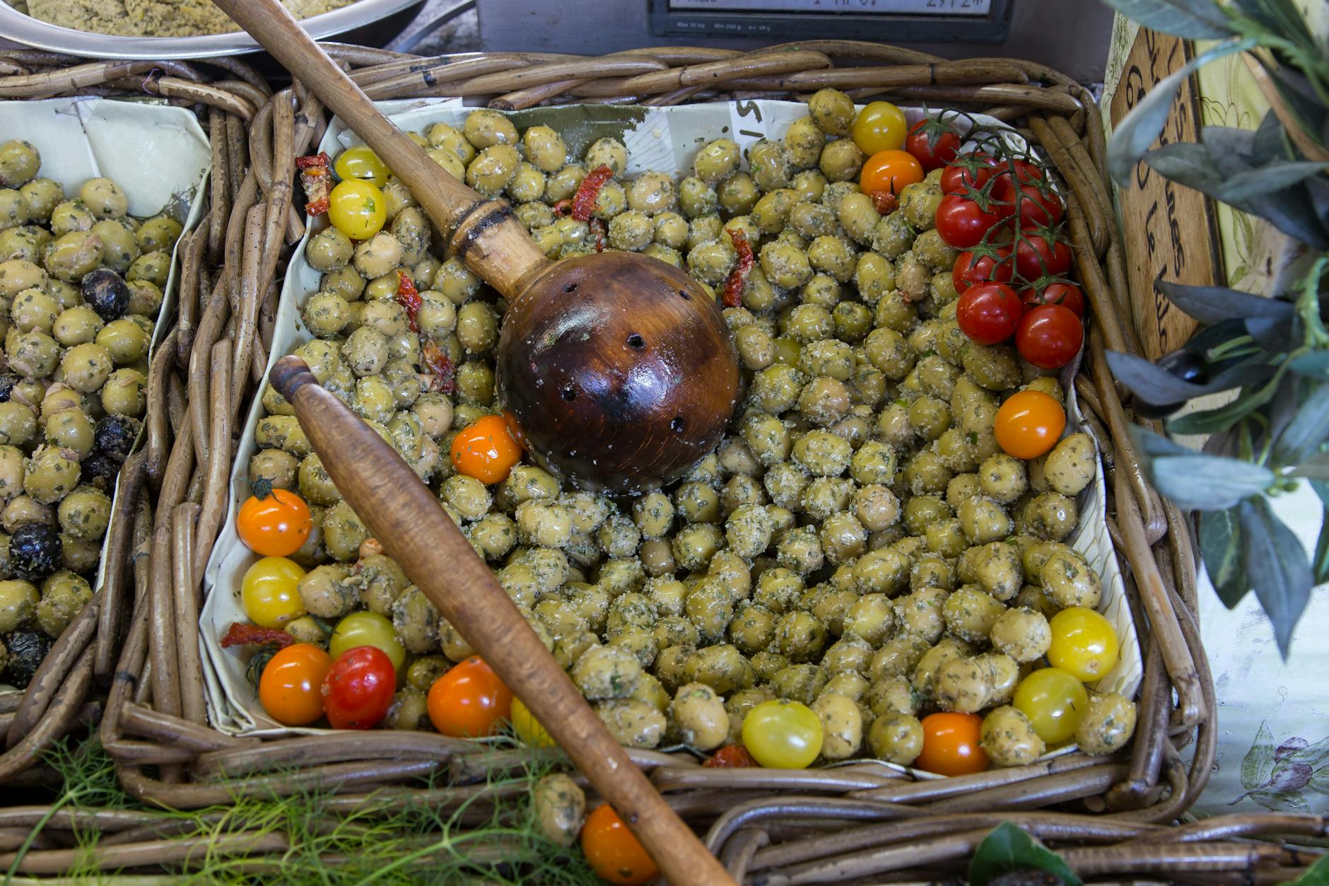 Display of marinated olives and bright red cherry tomatoes at a market stall in Provence