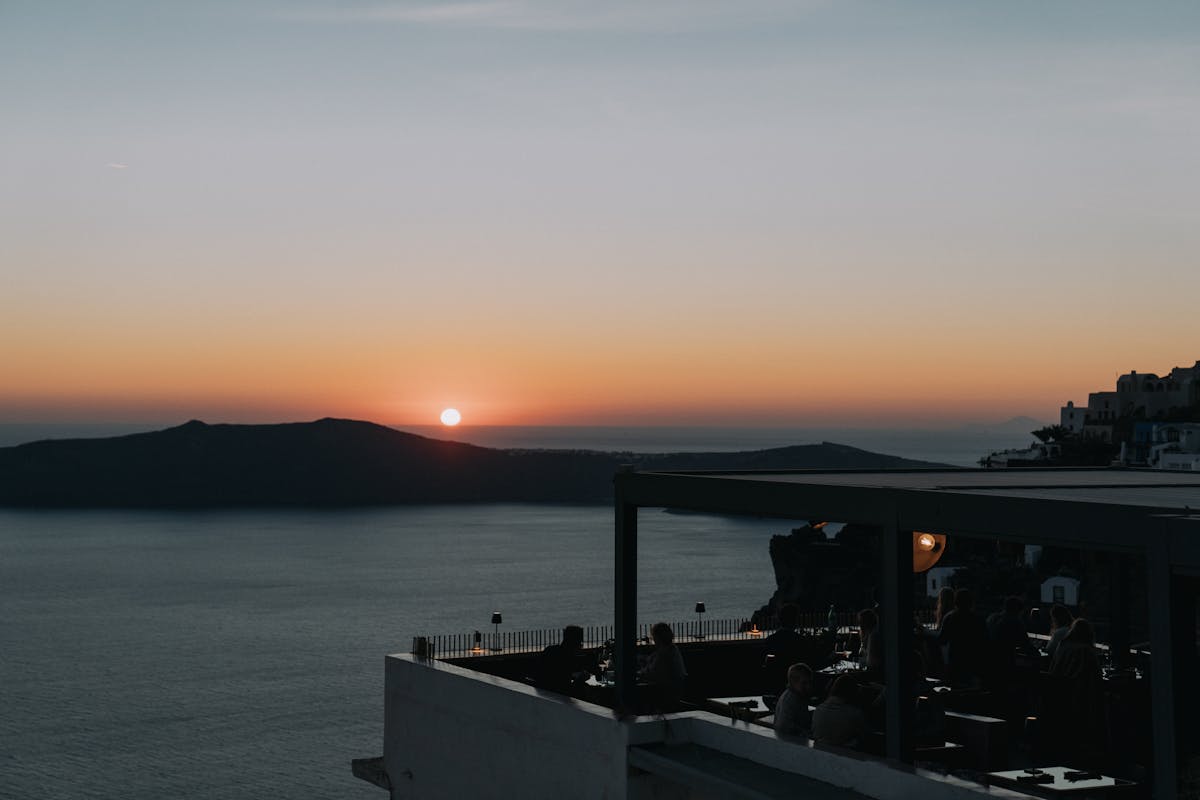 Cafe terrace in Santorini at sunset silhouetted against the sea