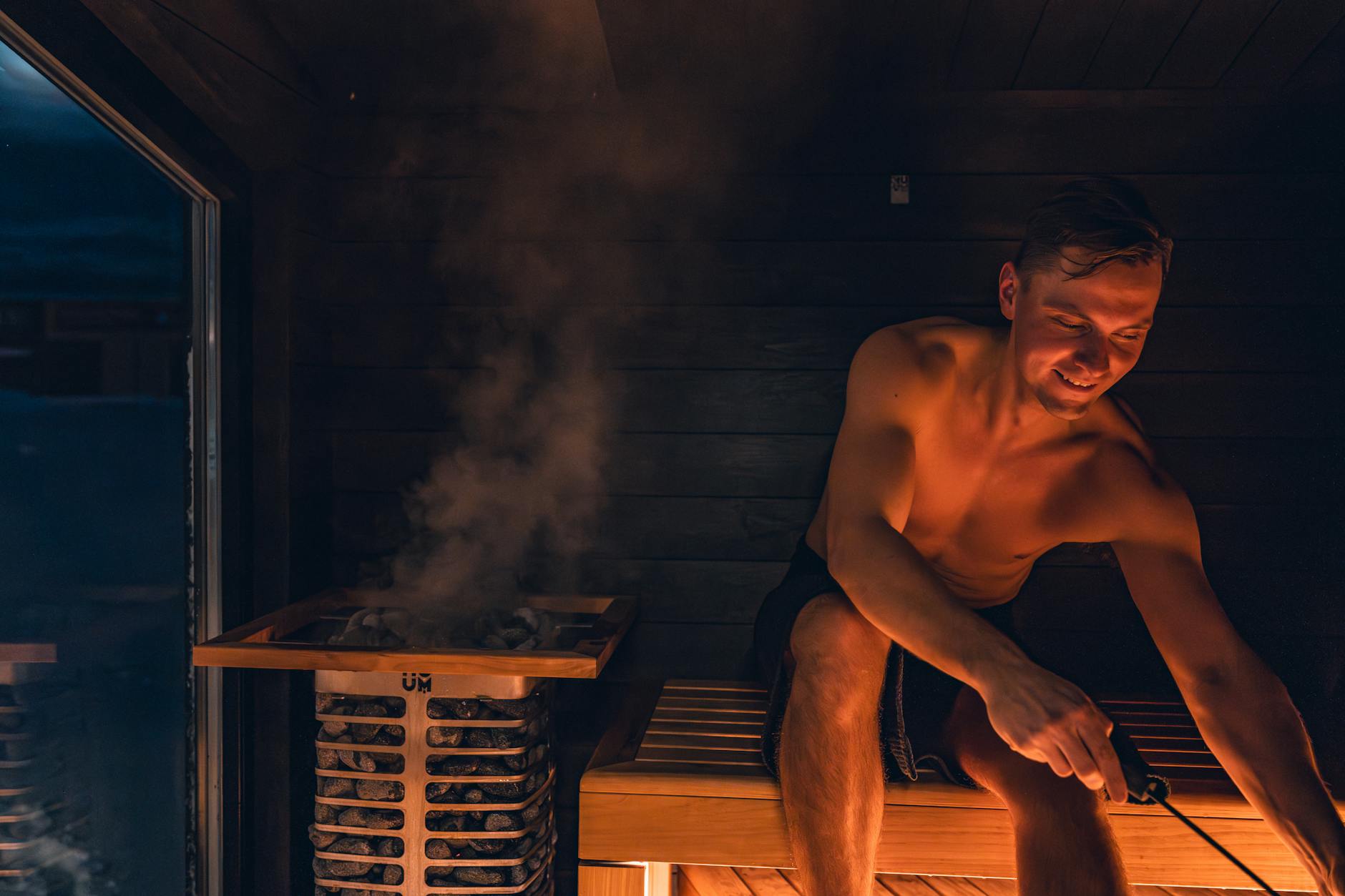 A man relaxing in a warm Nordic-designed sauna with wooden interior