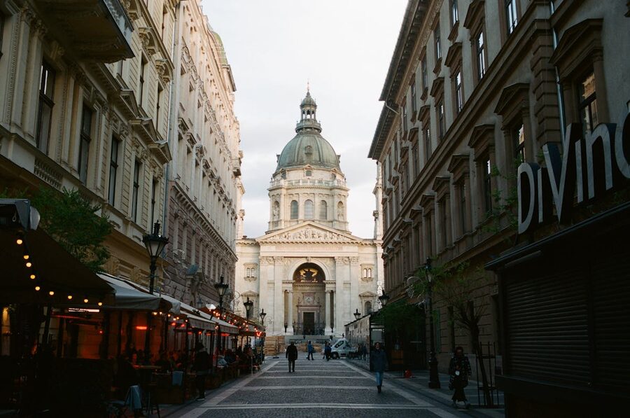 St. Stephen's Basilica viewed from a Budapest street with pedestrians walking toward it