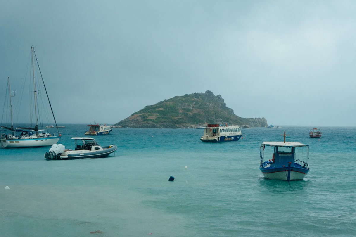 Boats anchored in turquoise waters near small Greek islands