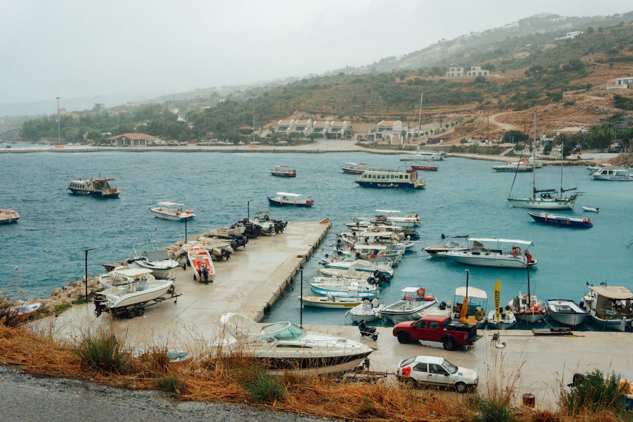 A scenic Greek harbor with colorful boats and waterfront buildings under clear skies