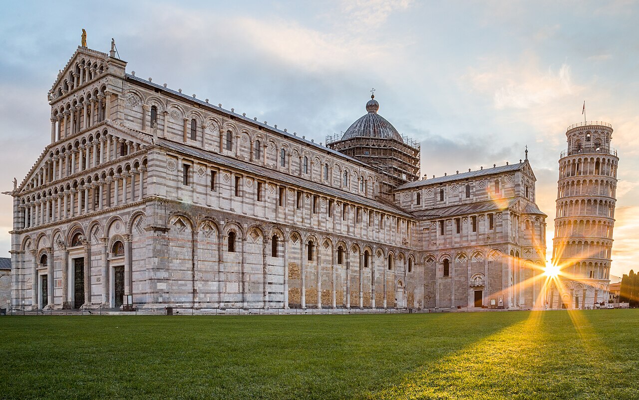 The Pisa Cathedral and Leaning Tower bathed in golden light at sunrise
