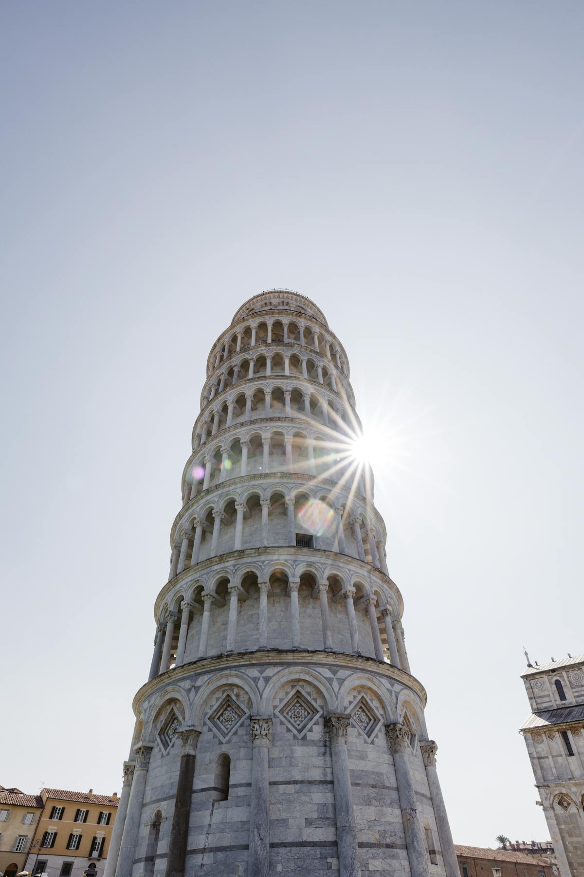 The Leaning Tower of Pisa captured from below with sunlight streaming through the columns